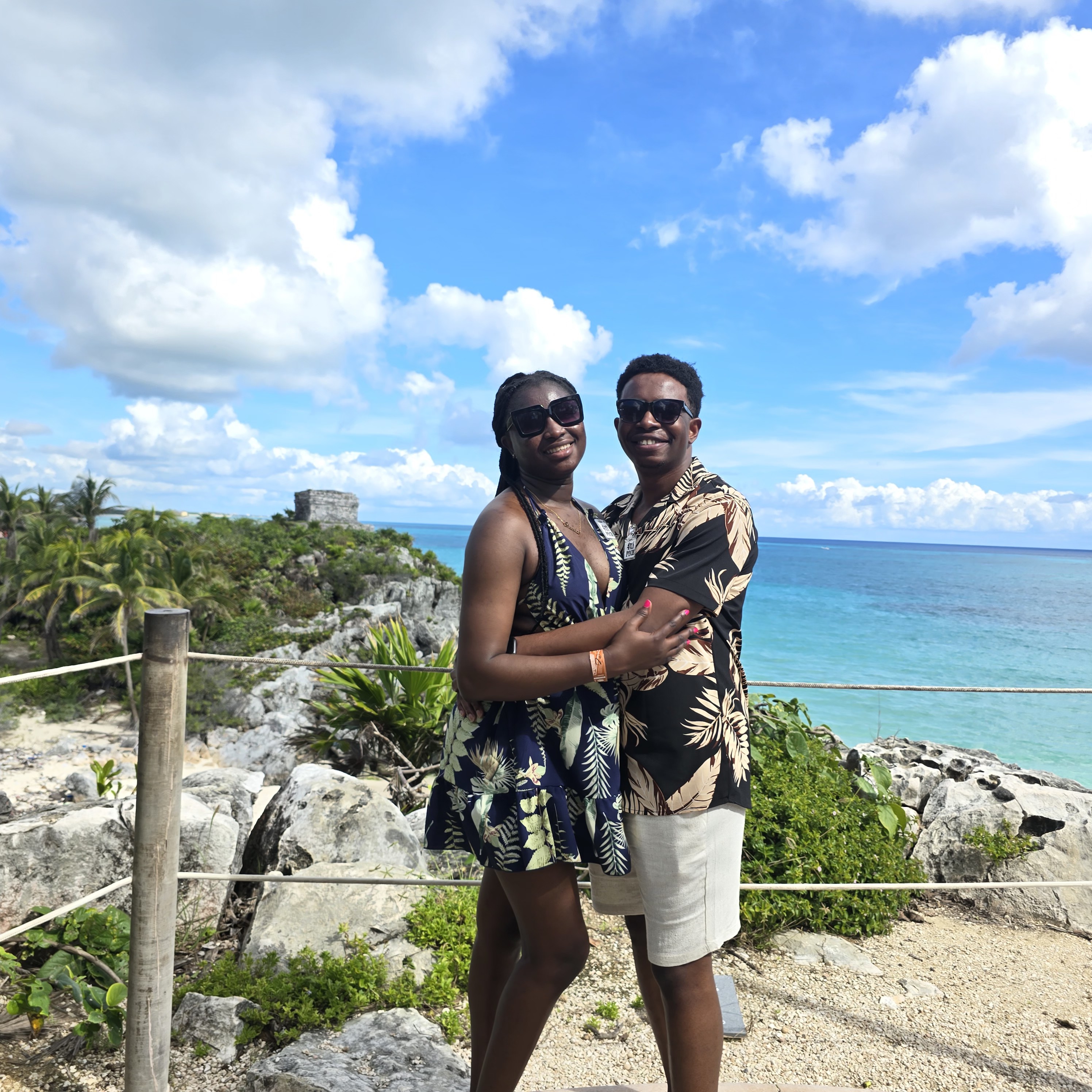 Paschal and Maryanne embracing at a sunny seaside overlook
