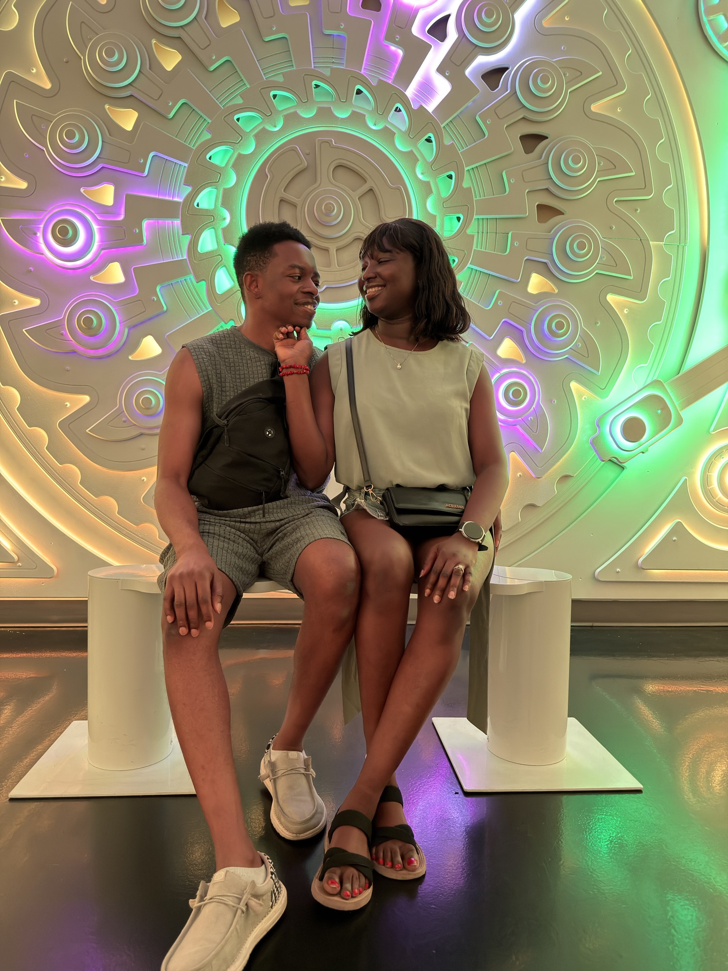 Paschal and Maryanne sitting together in front of a colorful illuminated pattern