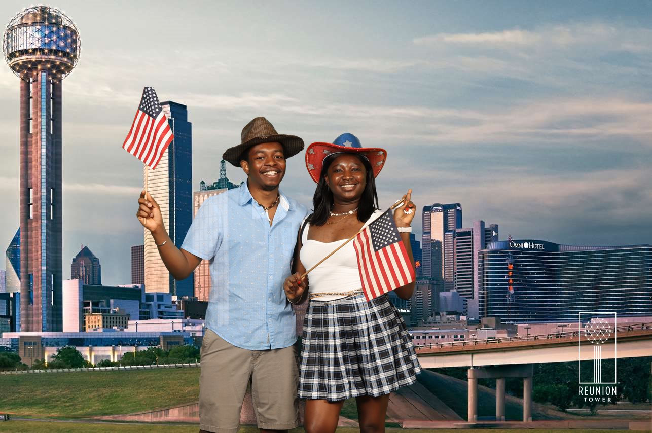 Paschal and Maryanne holding American flags in front of the Dallas skyline